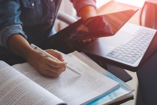 Woman with tablet, laptop, books Young woman with a pen in her hand works with a tablet, a laptop and books