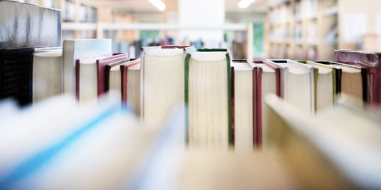 Public library bookshelf with books from behind